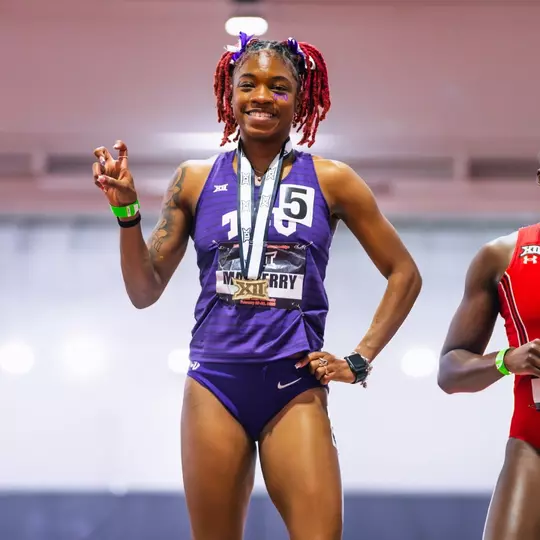 Indya Mayberry stands atop the podium with a gold medal after winning the 200m