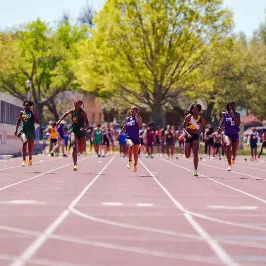 Athletes in the women's 100m dash running down the track