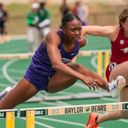 TCU's Amari Kiluvia jumping over a hurdle as she races down the track