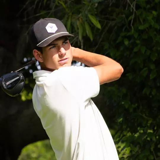 Sam Udovich swings a golf club and stares into the sun with a follow through