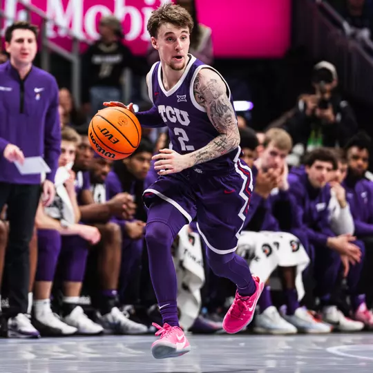 brock harding dribbles the ball up the floor wearing a purple uniform and pink shoes