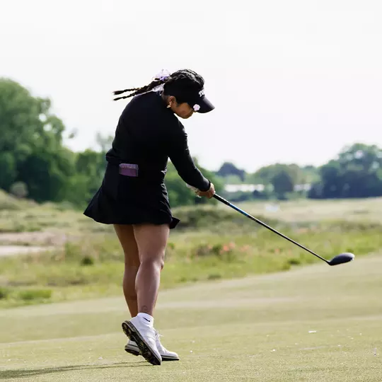 Kirstin Angosta connects with a golf ball on a tee shot.