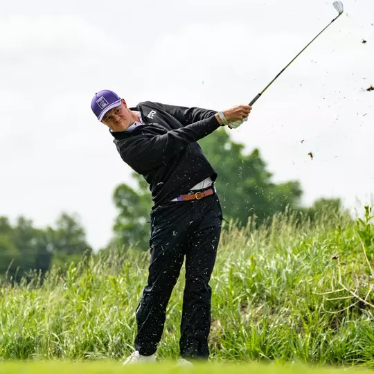 Lewis Wright hits an iron as grass falls from the end of the club.