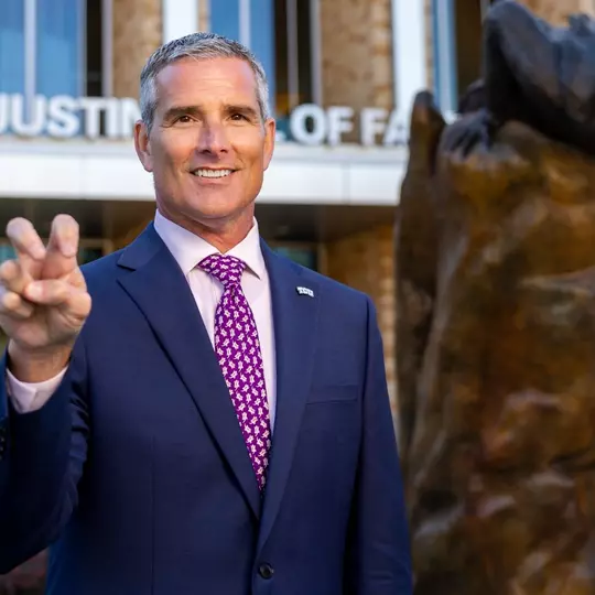 Mike Buddie gives a Go Frogs hand sign in front of Schollmaier Arena