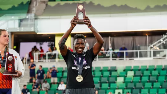 Irene Jepkemboi holds a trophy over her head after finishing third in the javelin throw