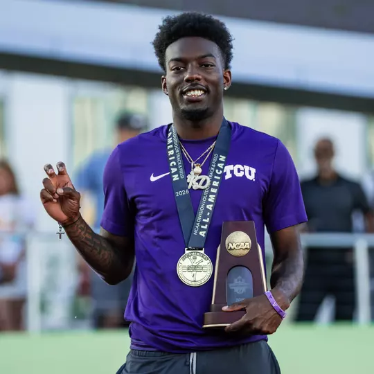 TCU's Jayden Douglas stands on the podium holding a trophy after finishing sixth in the 400m hurdles