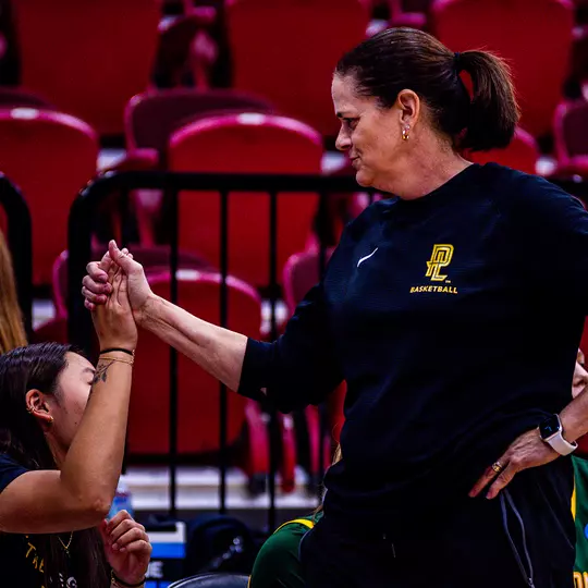 Charity Elliott high fives a player on the bench during a game
