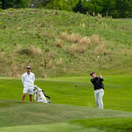 Bill Allcorn watches Charlie Wylie hit an approach shot.