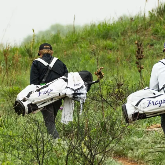 Charlie Wylie and Lewis Wright walk to their next hole carrying white golf bags.