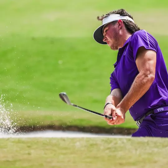 Cameron Kuchar swings out of the bunker wearing all purple
