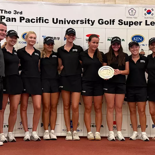 The TCU women's golf team poses together on stage with an engraved silver plate after finishing in second place at the Pan Pacific University Golf Super League tournament.