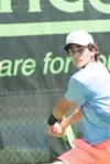 Jonah Dickson has the racket back while getting ready to swing a forehand at the tennis ball.