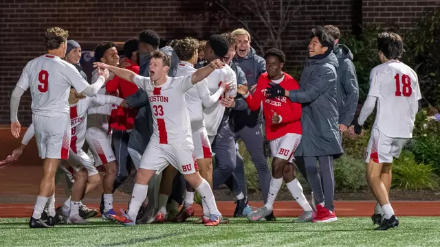 Men's Soccer team celebrates a goal scored against Holy Cross in a group gathering near the sideline