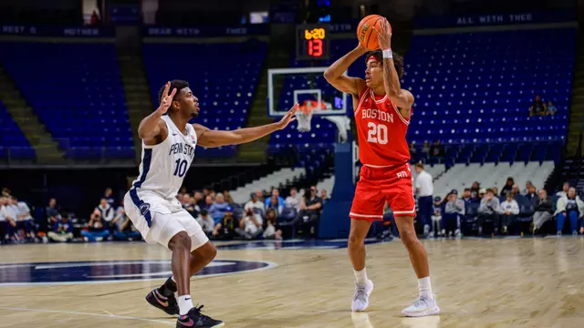 Michael McNair holds the ball above his shoulders looking to pass it with a Penn State defender close by