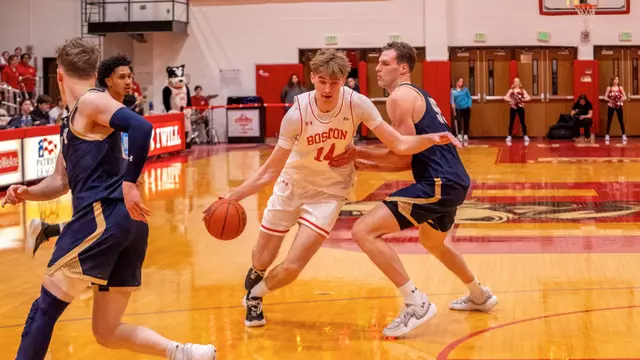 Ben Defty dribbles toward the hoop while defended by a Navy player