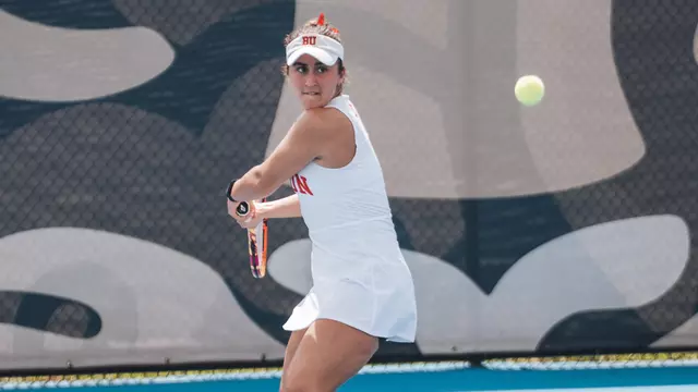 Gabriella Mikaul playing tennis in front of the FIU logo 2026