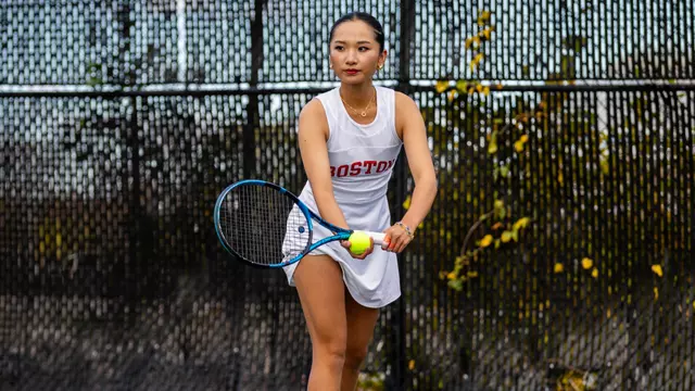 Emily Zhao prepares to serve in a white tennis dress