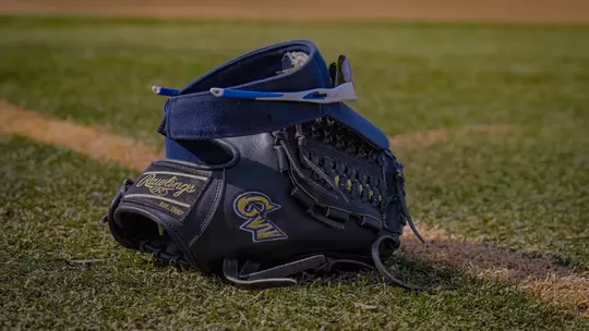 A pair of sunglasses and a visor resting on a softball glove that features the GW logo