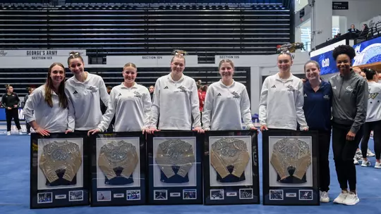 Seniors and GYM coaches pose together on senior night