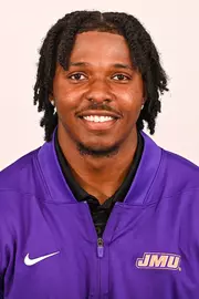 KD Mosley posed for headshot in purple quarter zip.