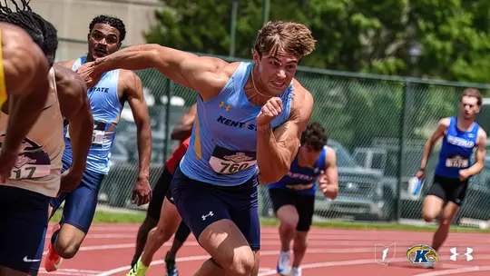 Kent State sprinter Ryan Gruss, wearing a light blue uniform and bib number 760, takes off as part of the baton exchange in the 4x100 relay race at the 2025 MAC Outdoor Track and Field Championships, with teammates and competitors visible in the background.