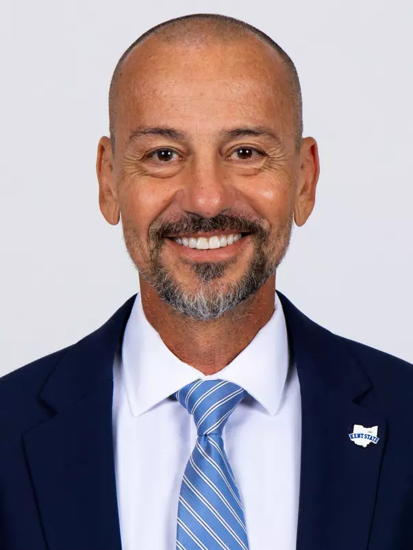 Headshot of Rob Marinaro smiling, wearing a navy blazer, white dress shirt, and light blue striped tie, with a Kent State lapel pin on his jacket.