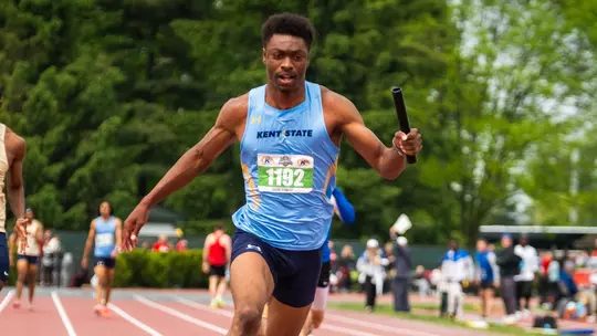 Kent State sprinter Jacob Stanley (bib 1192) drives down the track while carrying the relay baton during the MAC Outdoor Track and Field Championships.