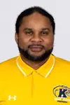 Headshot of Josh Cribbs smiling, wearing a gold Kent State Football Under Armour polo shirt with the Golden Flashes logo and white collar trim, with short dark hair and light stubble.