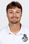 Studio headshot of a smiling young man with light brown hair and a trim goatee, wearing a white collared Kent State baseball polo shirt against a plain white background.