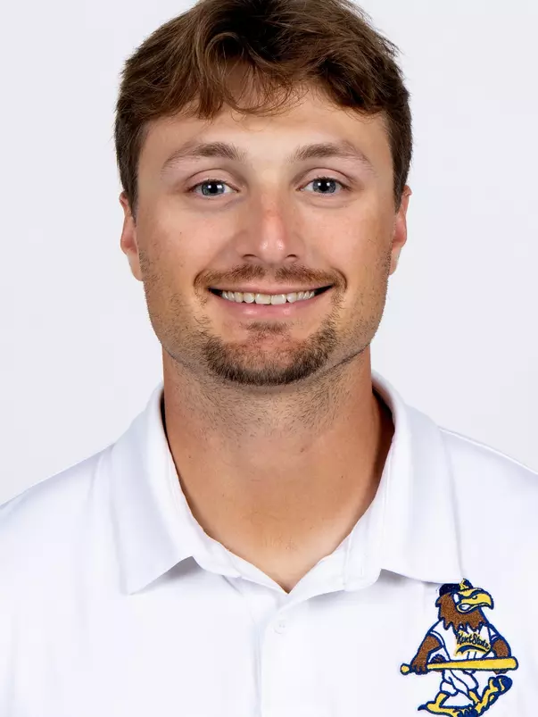 Studio headshot of a smiling young man with light brown hair and a trim goatee, wearing a white collared Kent State baseball polo shirt against a plain white background.