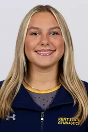 head shot of a Kent State gymnastics student-athlete smiling wearing a navy blue jacket on a white backdrop