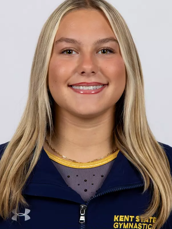 head shot of a Kent State gymnastics student-athlete smiling wearing a navy blue jacket on a white backdrop