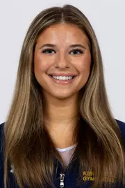 head shot of a Kent State gymnastics student-athlete smiling wearing a navy blue jacket on a white backdrop