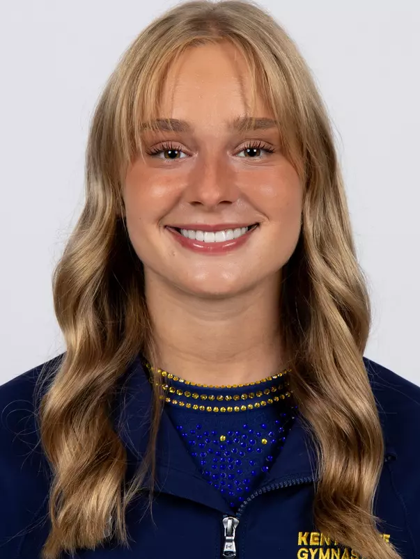 head shot of a Kent State gymnastics student-athlete smiling wearing a navy blue jacket on a white backdrop