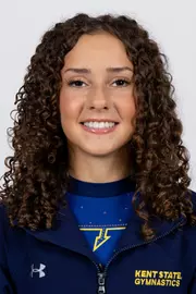 head shot of a Kent State gymnastics student-athlete smiling wearing a navy blue jacket on a white backdrop