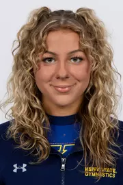 head shot of a Kent State gymnastics student-athlete smiling wearing a navy blue jacket on a white backdrop