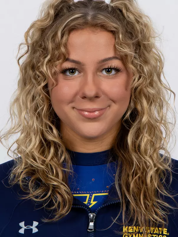 head shot of a Kent State gymnastics student-athlete smiling wearing a navy blue jacket on a white backdrop