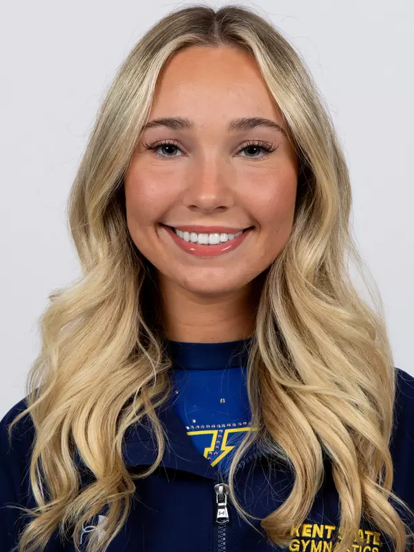 head shot of a Kent State gymnastics student-athlete smiling wearing a navy blue jacket on a white backdrop
