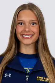 head shot of a Kent State gymnastics student-athlete smiling wearing a navy blue jacket on a white backdrop
