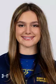 head shot of a Kent State gymnastics student-athlete smiling wearing a navy blue jacket on a white backdrop