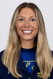 head shot of a Kent State gymnastics student-athlete smiling wearing a navy blue jacket on a white backdrop