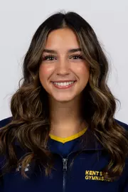 head shot of a Kent State gymnastics student-athlete smiling wearing a navy blue jacket on a white backdrop