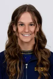 head shot of a Kent State gymnastics student-athlete smiling wearing a navy blue jacket on a white backdrop