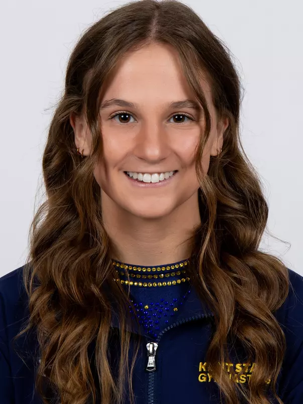 head shot of a Kent State gymnastics student-athlete smiling wearing a navy blue jacket on a white backdrop