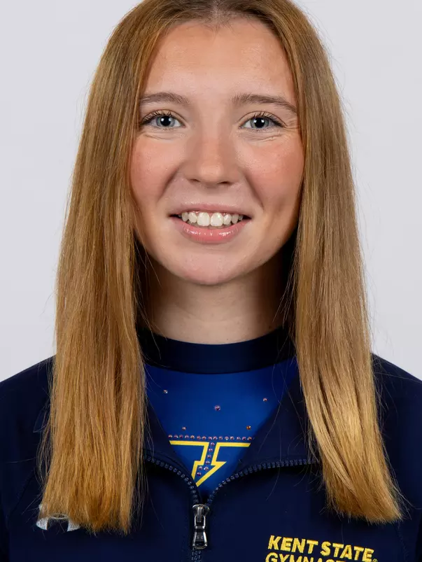 head shot of a Kent State gymnastics student-athlete smiling wearing a navy blue jacket on a white backdrop