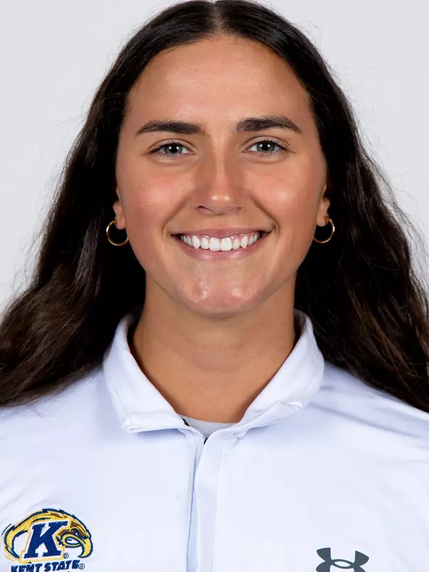 Headshot of a smiling woman with long dark hair wearing a white Kent State Softball polo shirt against a plain background.