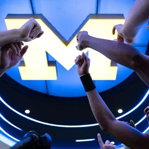 Men's basketball team huddle inside locker room block M