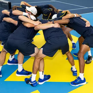 Men's tennis team huddle indoors