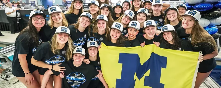 Michigan Women's swim & dive team with a Michigan Block M flag