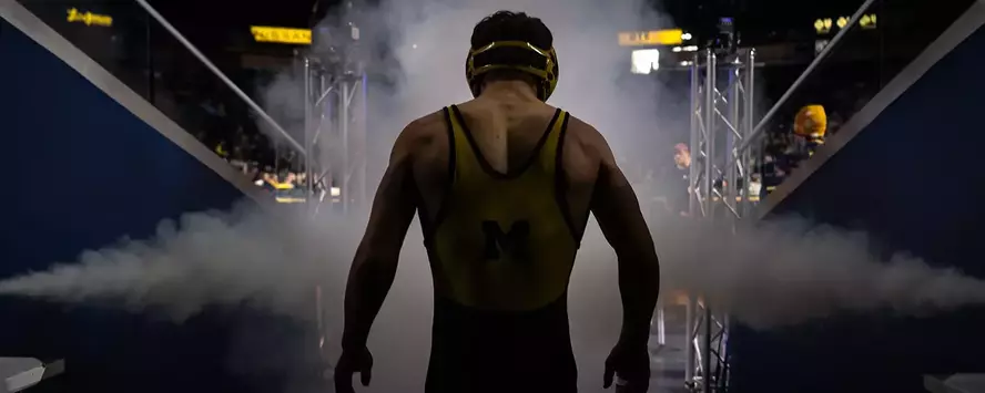 Michigan wrestler walking out of the Crisler tunnel with smoke